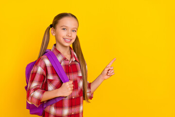 Photo of adorable funny schoolkid dressed plaid shirt pointing empty space isolated yellow color background