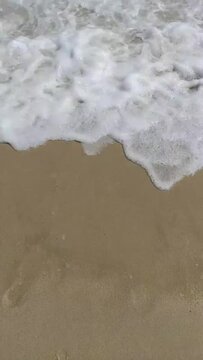 Fin del verano. Una ola borra el texto "fin" escrito en la arena de la playa.