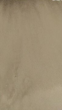 Fin del verano. Una ola borra el texto "fin" escrito en la arena de la playa.