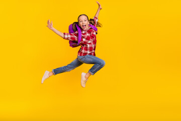 Photo of sweet impressed schoolkid dressed plaid shirt jumping high running fast empty space isolated yellow color background
