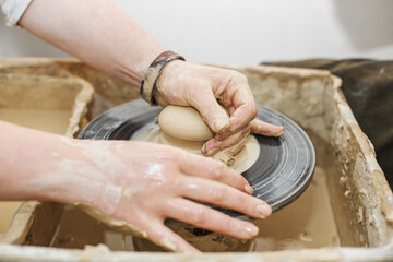 Potter girl works on potter's wheel, making ceramic pot out of clay in pottery workshop. Art concept