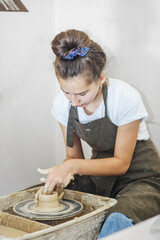 Teenage girl creates pottery in pottery workshop. Creative process. Hobby and learning concept