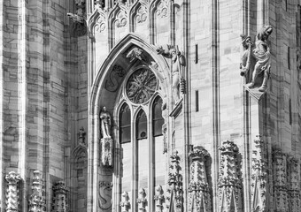 Part of the wall of the Catholic Cathedral with a window and many marble figures and elements. Black and white photo