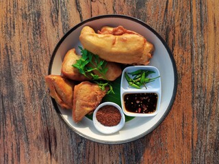 Fried Tofu, garnished with Cosmos Leaf. Condiment with Black Sweet Soy Sauce and Chili, isolated on wooden vintage wooden table. Afternoon sunlight outdoors