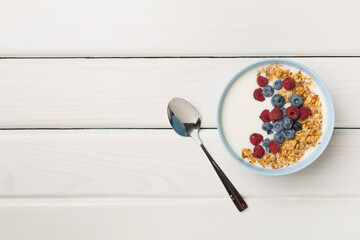 Bowl with granola, yogurt and fresh berries on wooden background, top view