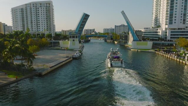 Luxury boat on cruise through city. Forwards tracking of yacht approaching bridges over river. Miami, USA