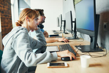 Obraz premium Students learning in computer classroom. Young man preparing for test on computer. Girl writing essay and making notes using computer. Focused students studying for college exams