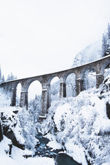 Obraz premium Mountain landscape with Sainte Marie bridge covered with snow in Les Houches, Chamonix valley, Eastern France. Viaduct bridge built to carry a railway over water.