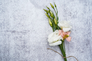 Bouquet of white and apricot lisianthus flowers on concrete background. Space for text.