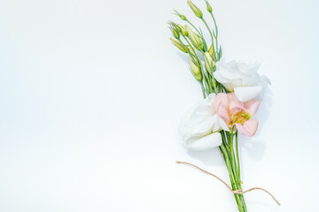Bouquet of white and apricot lisianthus flowers on white background. Space for text.