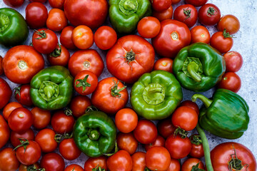 Various sizes of red, homegrown tomatoes, green peppers, and beans on a concrete background. Background, graphic resource.