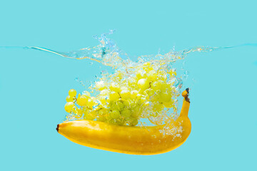 White grapes and banana dropped in water on blue