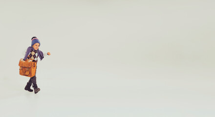 Portrait of little boy, child in winter clothes, hat and sweater carrying vintage briefcase isolated over grey studio background