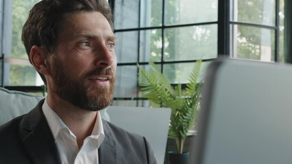 Happy dreaming smiling Caucasian bearded adult 40s man work with computer online write article looking away dreaming thinking pondering business strategy plan smile satisfied typing laptop in office