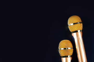 Two golden microphones isolated on black background close up