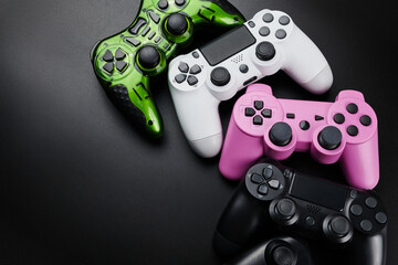 Many different video game controllers, multicolored joysticks for game console isolated on black background. Gamer controlling devices close-up