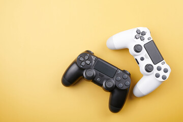 Two video game controllers, joysticks for game console isolated on yellow background. Gamer controlling devices close-up