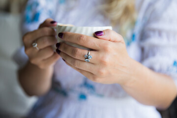 Woman's hand with ring holding cup of cappuccino