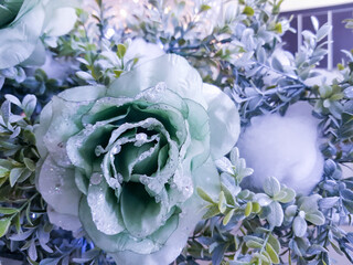 Frozen rose in white frost. Rose petals in small ice crystals surrounding a flower, decorative decoration of a Christmas tree, selective focus