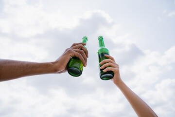 partial view of multiethnic friends toasting with fresh beer.