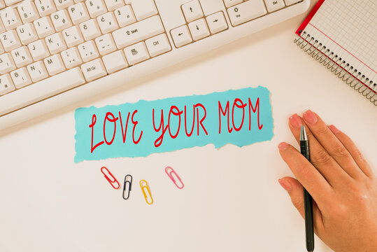 Sign Displaying Love Your Mom. Business Overview Have Good Feelings About Your Mother Loving Emotions Notebook With New Message On Desk With Pens, Headphones And Paperclips.