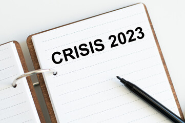 Crisis 2023 inscription on a notebook on a desk, business concept