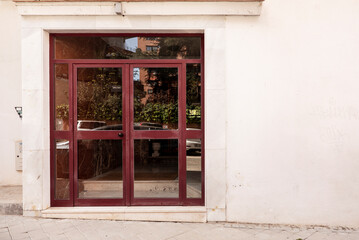 Portal of a house with red metal and glass doors on a white facade