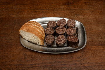 Spanish tapa of chopped black pudding ready to fry with slices of village bread on a metal tray