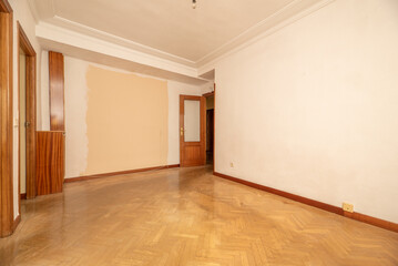 Empty living room of a residential house with herringbone oak parquet floors and wooden carpentry on the doors and skirting boards