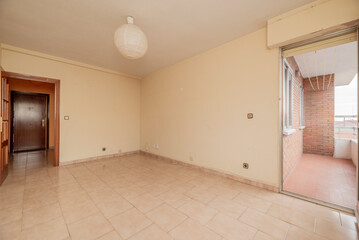 empty room has square tile stoneware floor, cream painted wall with gotelet, access to a terrace with clay floors and reddish wooden door with glass window