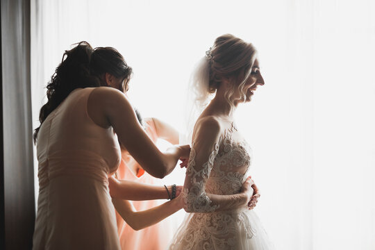 Hands of bridesmaids on bridal dress. Happy marriage and bride at wedding day concept