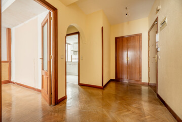 Entrance hall of a house with cherry wood door, herringbone oak parquet flooring, access to multiple rooms, fitted wardrobes and cream yellow painted walls