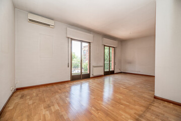 Empty living room of a residential house with oak parquet floor, two large aluminum and glass...