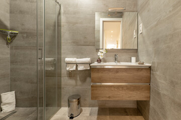 Bathroom with oak chest of drawers with imitation marble tiles, frameless mirror on the wall,...