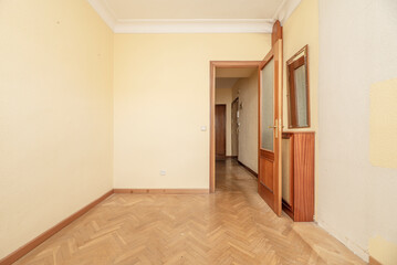 Empty room in a residential house with oak parquet flooring, plaster shingle on the ceiling and cream painted walls