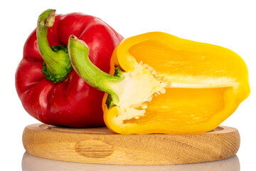 One whole and one half, organic ripe juicy bell pepper, on a round bamboo tray, close-up, on a white background.