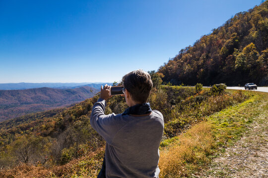 Woman taking picture with mobile phone from lookout point at Pisgah National Forest, North Carolina, USA