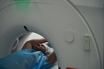 Man lies in tomography camera on diagnostic procedure upper body
