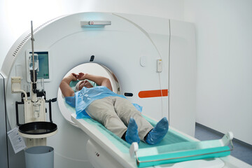 Patient lies in chamber of tomograph on diagnostic procedure chest