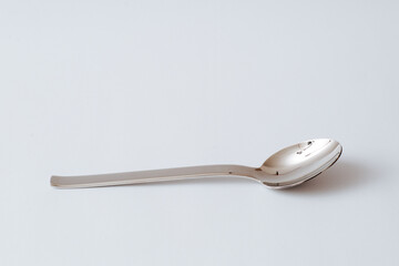 Stainless steel teaspoon on white background, kitchenware, copy space, close-up