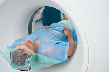 Man is undergoing abdominal tomography procedure in clinic