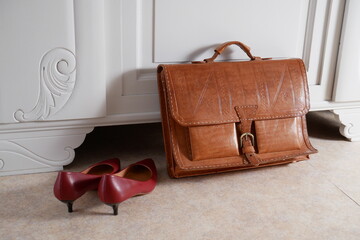 Cartable en cuir et chaussures de femme devant un meuble vintage 