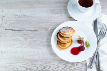 Pancakes in a plate, a cup of tea on a light table with a place for writing text.