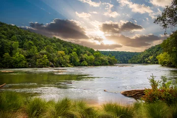  a gorgeous summer landscape along the Chattahoochee river with flowing water surrounded by lush green trees, grass and plants with powerful clouds at sunset in Atlanta Georgia USA © Marcus Jones