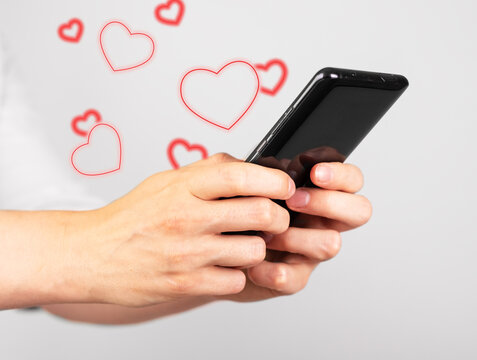 Hands holding phone for sending love messages. Woman texting letter to lover. Smartphone with red hearts. Romantic chatting via messengers, social media.