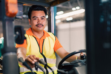 Portrait of male Asian driver driving forklift to shipping delivery in the warehouse distribution....