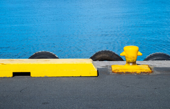 Yellow Dock Cleat and Mooring Equipment on a Dock With Blue Ocean in the Background.