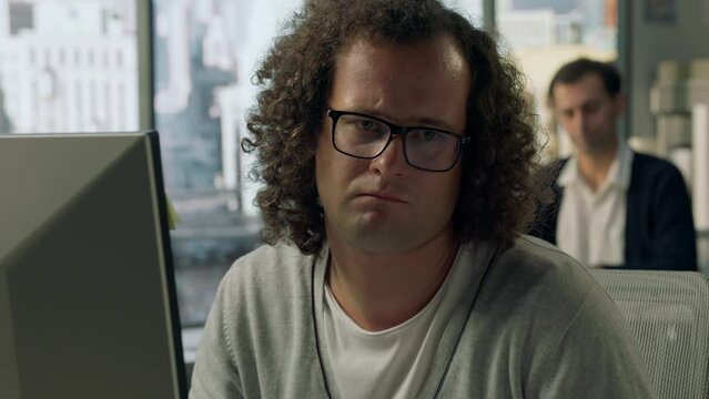 SLOW ZOOM IN Nerdy Caucasian employee is frustrated after recieving extra work on Friday evening