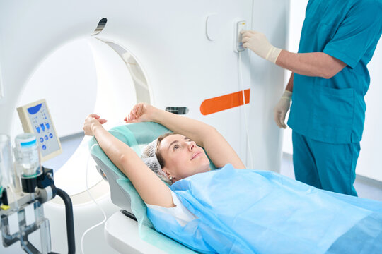 Woman with her arms outstretched lies in a tomography room