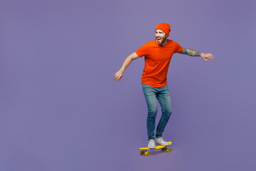 Full body side view amazed happy young european man 20s he wears red hat t-shirt rides pennyboard skateboard isolated on plain pastel light purple background studio portrait. People lifestyle concept. © ViDi Studio